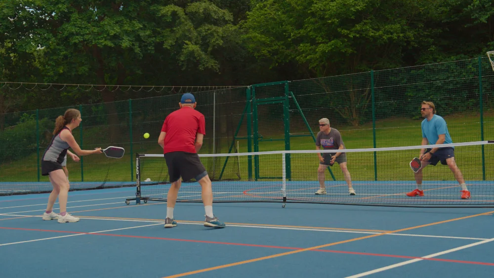 Players in the middle of a pickleball rally on the outdoor courts at Woodbridge School, Suffolk. Ran by RallyPoint by Suffolk Pickleball Company.